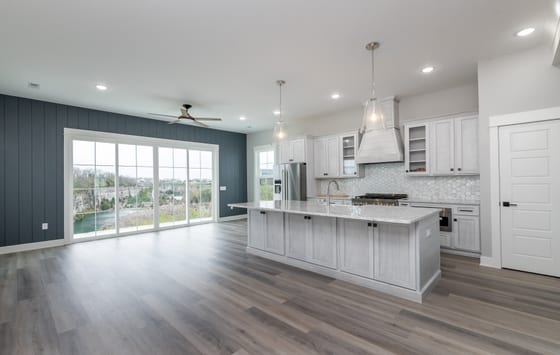 Open-plan kitchen and living area with a quartz-topped island, navy shiplap accent wall, and sliding doors onto a quarry view