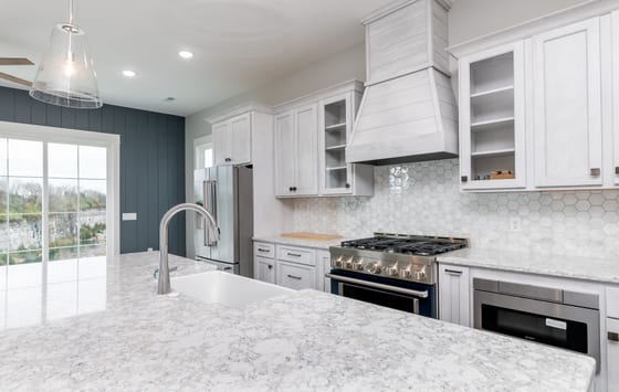 View across the quartz island to the range wall, with a navy shiplap wall and the quarry visible through sliding doors
