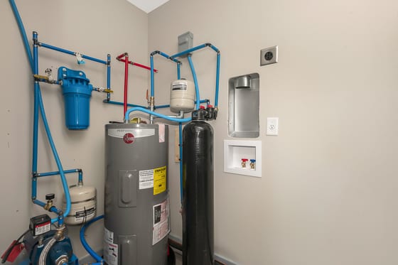 Mechanical room with water heater, water softener, and a run of blue PEX plumbing